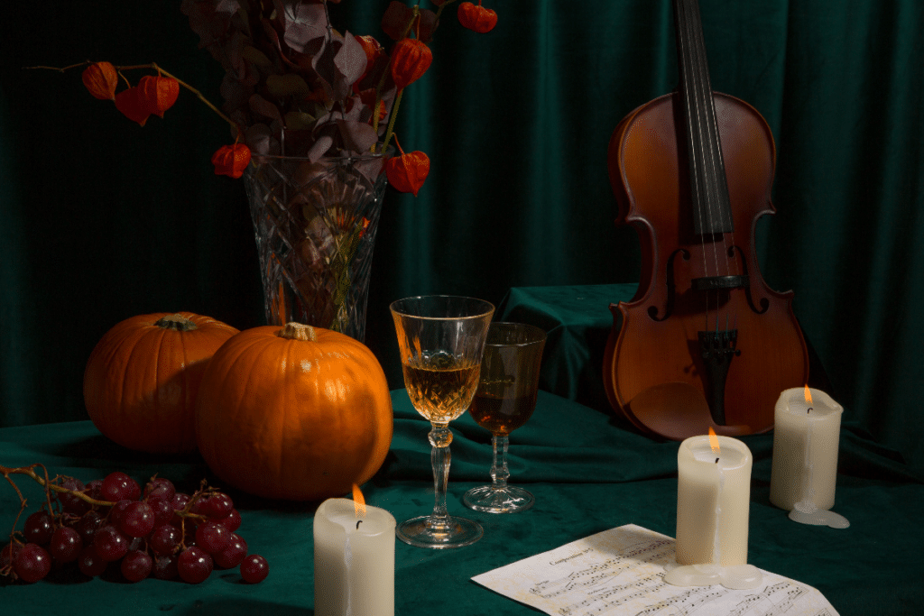 Pumpkins, wine glasses, candles, violin and more on a table for a Candlelight concert