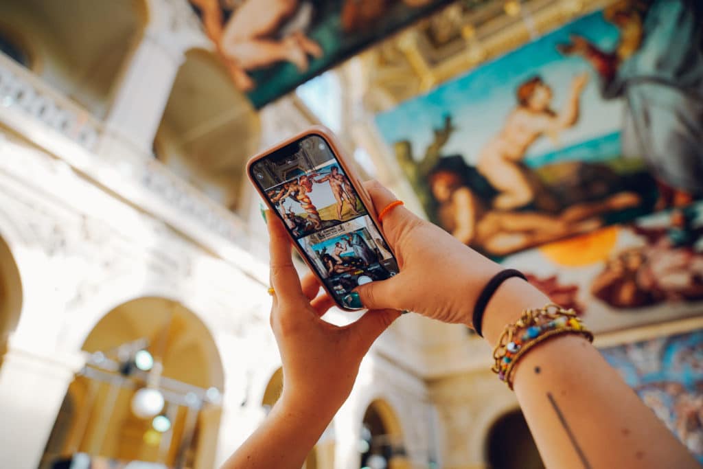 visitante a tirar uma foto na exposição imersiva sobre Michelangelo que leva a Capela Sistina